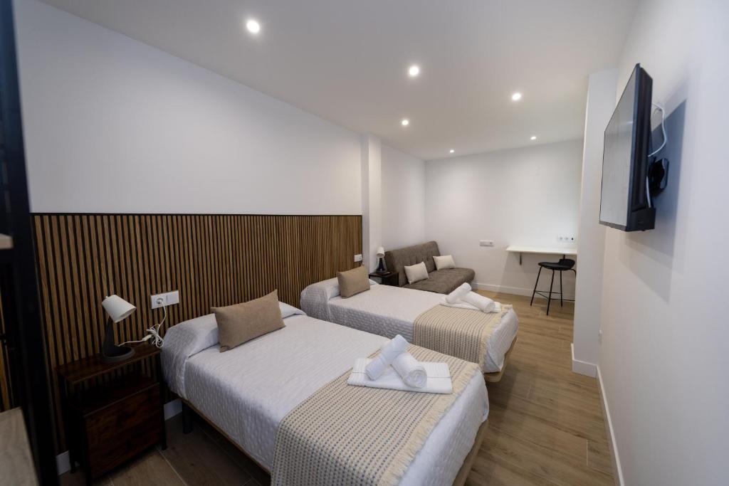 Una habitación de hotel con dos camas y un televisor. en Nido PADRON, en Padrón