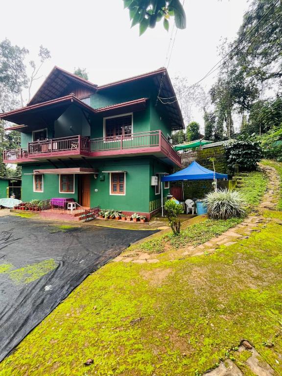 a green house with a black roof at Quiet quarters Estate Stay in Napoklu