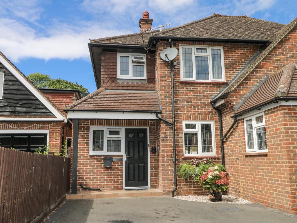 ein rotes Backsteinhaus mit einer schwarzen Tür in der Unterkunft Sunnyfield Cottage in Coulsdon