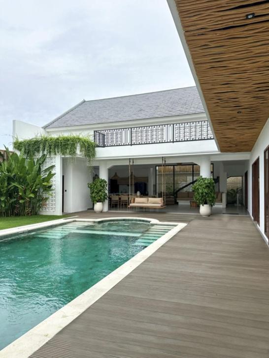 a house with a swimming pool and a wooden deck at Casa De Cuentos Bali in Denpasar