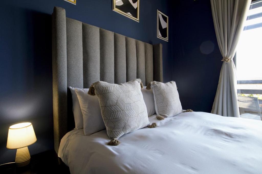 a blue bedroom with a bed with white pillows at Secure Designer Jozi Apartment With Balcony & Ellis Park Views - Hallmark House in Johannesburg