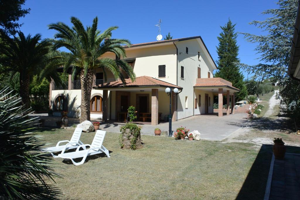 ein Haus mit zwei Gartenstühlen und einer Palme in der Unterkunft Il Gheriglio in Torano Nuovo