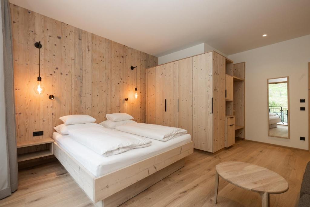 a bedroom with a white bed and wooden walls at Hotel Kristall in Grossarl