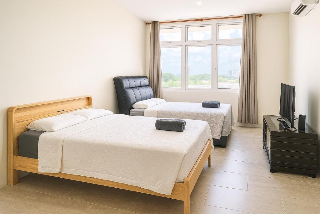 a hotel room with two beds and a tv at Riverine Diamond 7 RDB Studio CK - Free 1 Parking, Netflix & Cozy Retreat Couples, Families in Kuching