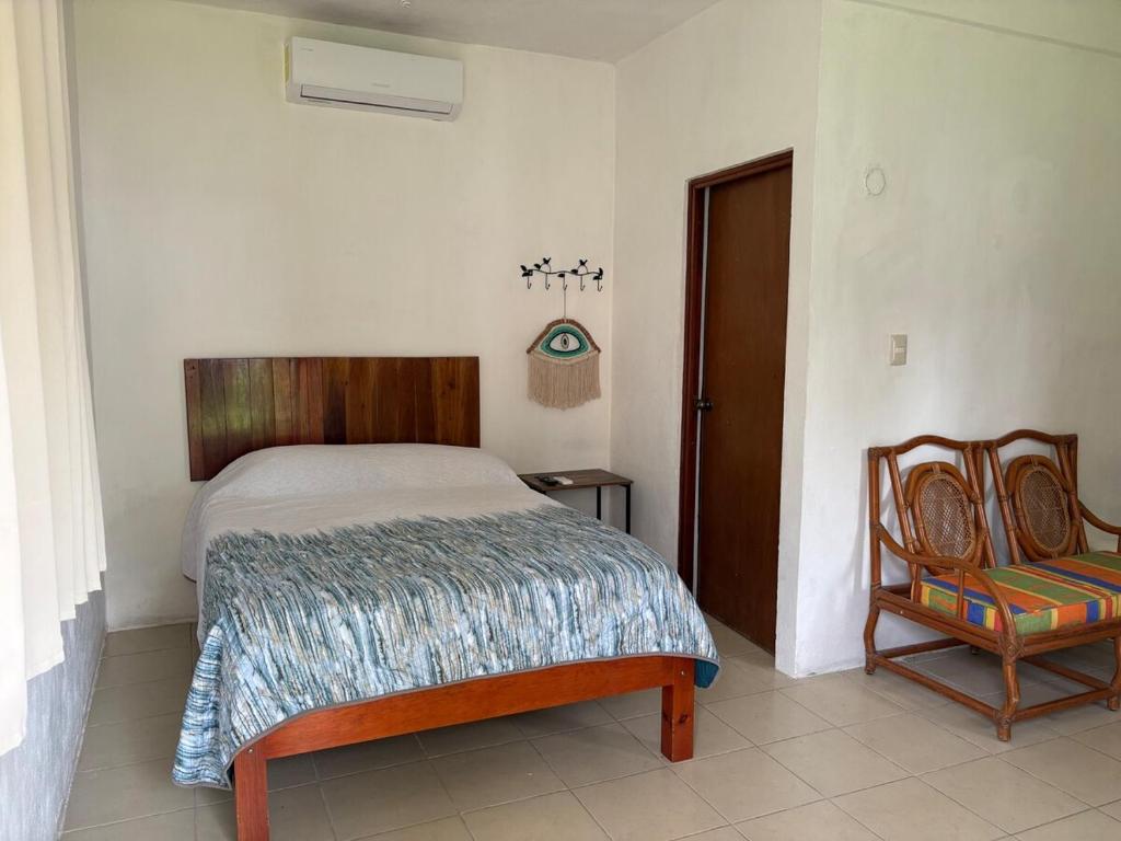 une chambre avec un lit et une chaise dans l'établissement GalHaus, à Bacalar