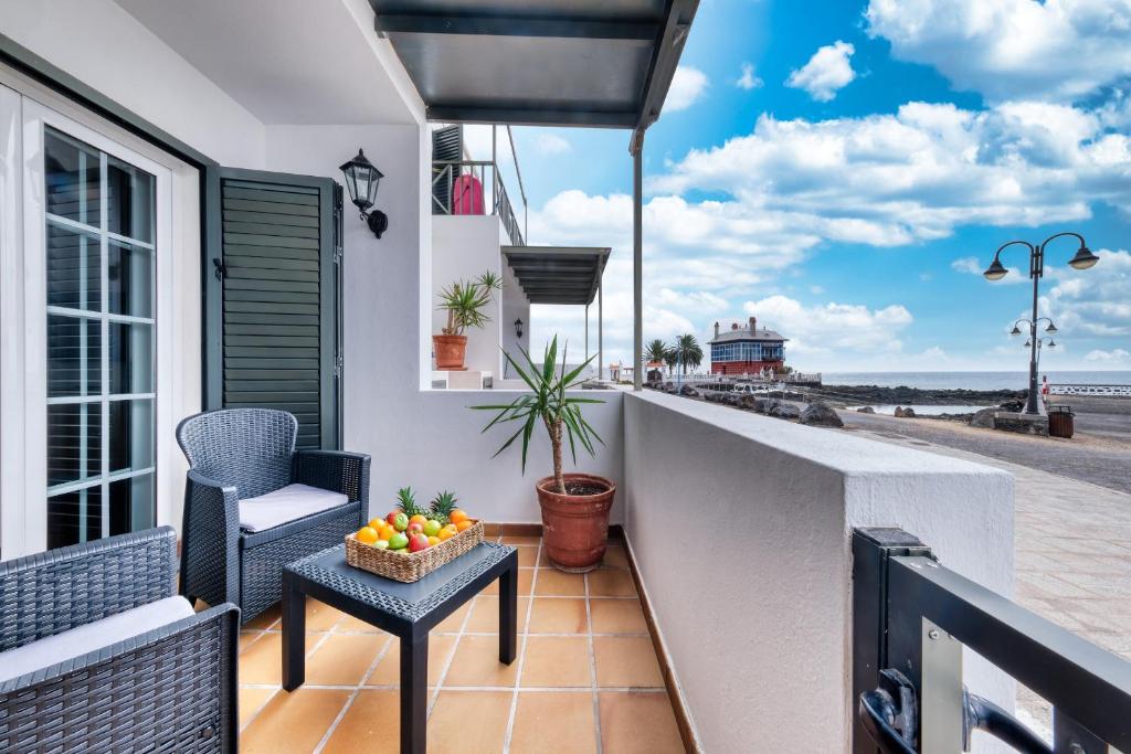 a balcony with chairs and a bowl of fruit on a table at Apartamento El Charcon A - 10 meters to the Beach By Lanzarote Vacation Homes in Arrieta