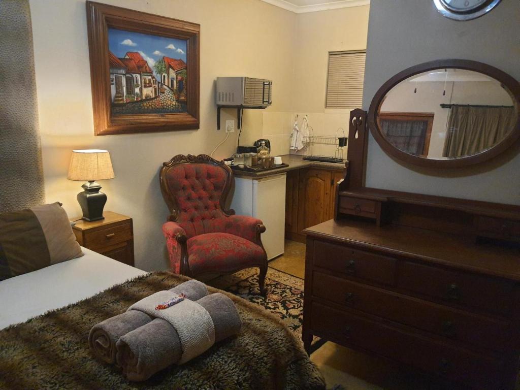 una camera da letto con un letto, uno specchio e una sedia di Gemsbok Cottage a Bethlehem