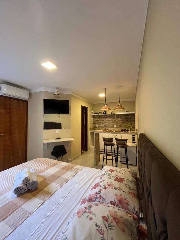 a bedroom with a large bed and a kitchen at Casinhas da Vila in Itacaré
