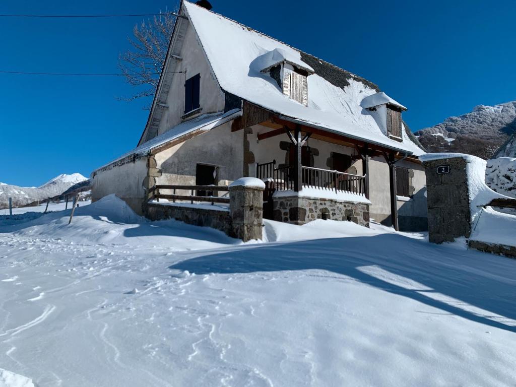 ein schneebedecktes Haus mit einem schneebedeckten Hof in der Unterkunft Gîte À La Ferme Au Puy Mary in Mandailles