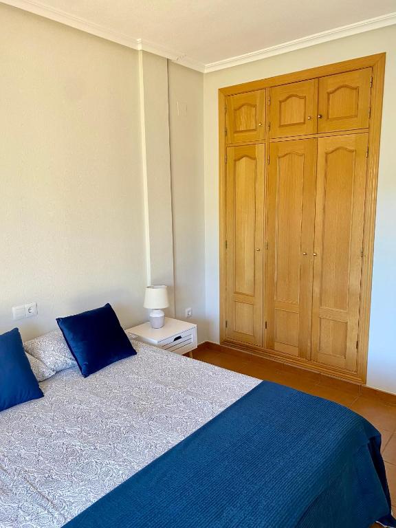 Schlafzimmer mit einem blauen Bett und einem Holzschrank in der Unterkunft Habitación en Bonalba con vistas al campo de golf in Mutxamel