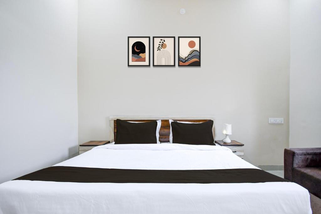 a bedroom with a white bed with three pictures on the wall at Hotel O KVR snuggle in Bilāspur