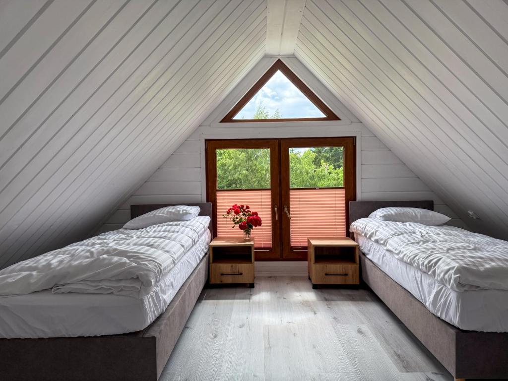 two beds in a attic room with a window at Cicha Przystań w Jezierzanach in Jarosławiec