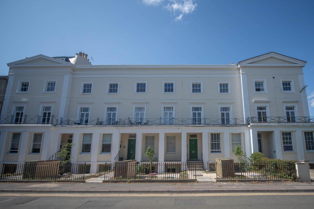 a white building with a fence in front of it at The Cheltenham Suites - Fabulous 1 Bed Apartment in Cheltenham