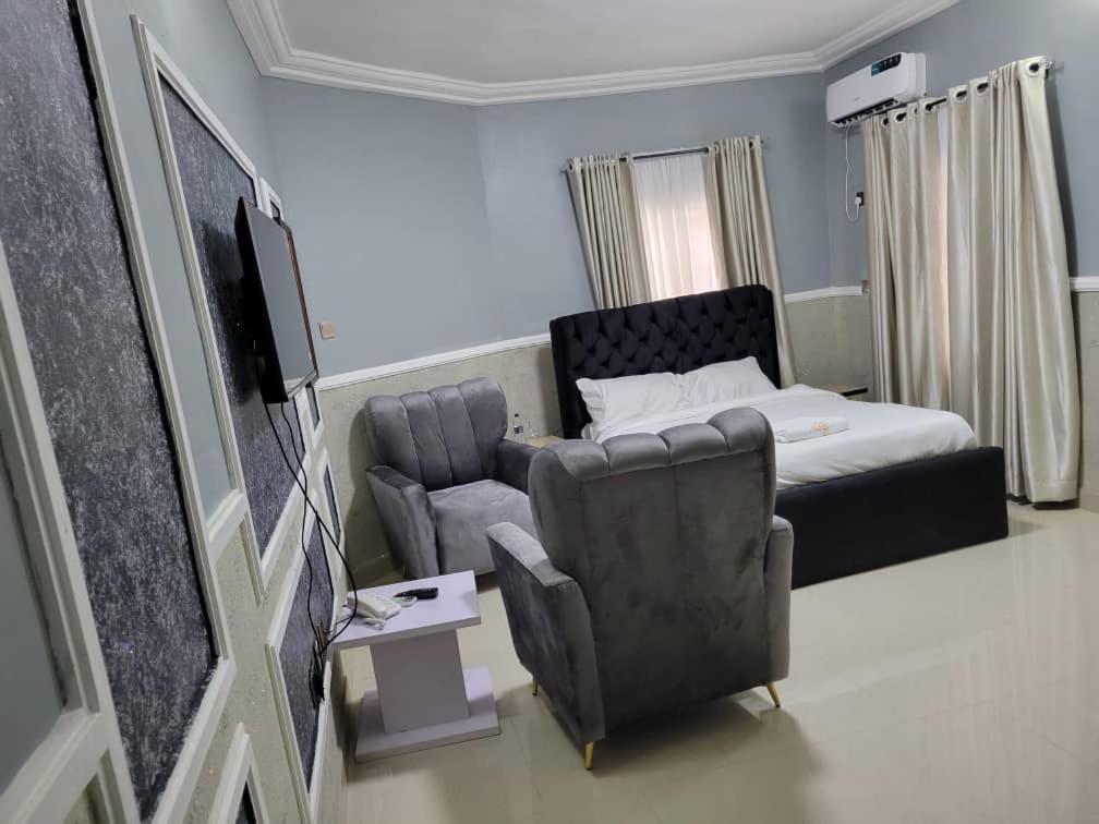 a room with a bed and a couch and a chair at International Royal Hotel in Owerri
