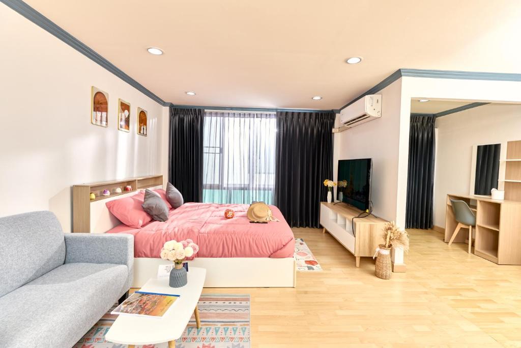 a bedroom with a pink bed and a couch at Ten Place at Srinakarin in Bangkok