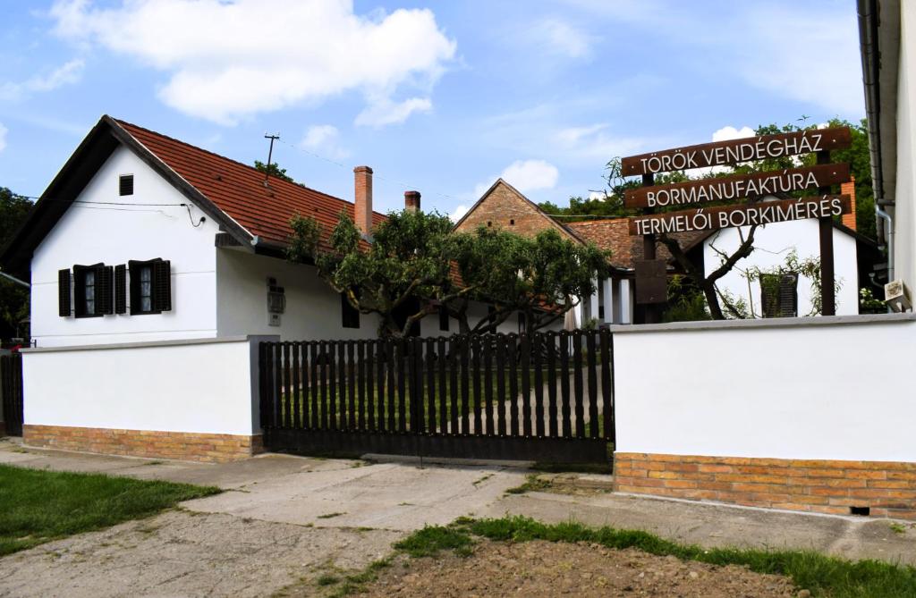 a white house with a black fence and a sign at Villány Outback in Kisjakabfalva