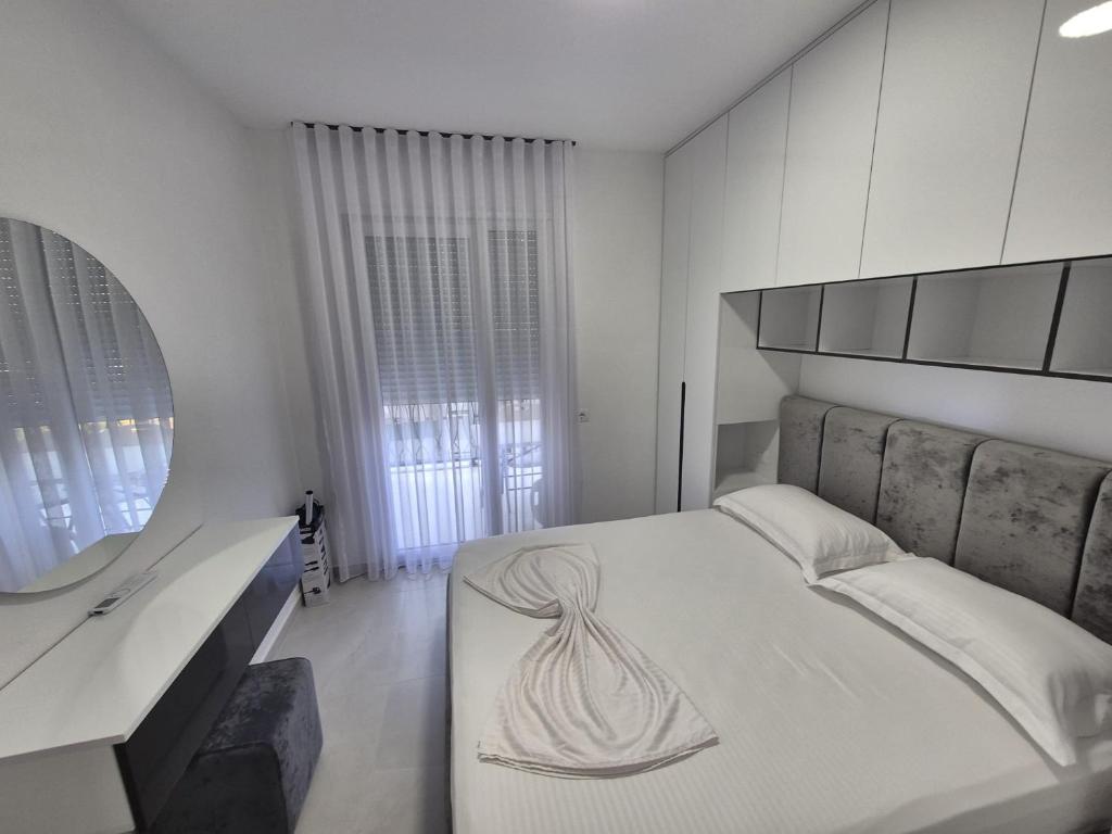 a white bedroom with a large bed and a mirror at New Comfort Apartment in Golem