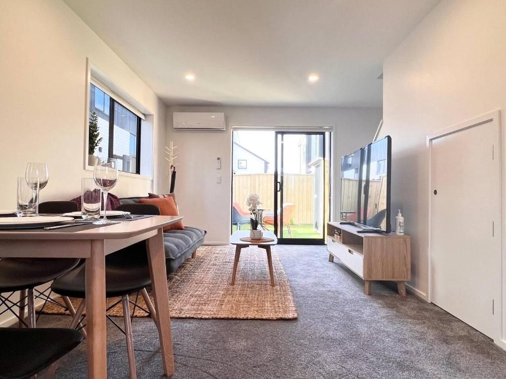 a living room with a table and a couch and a tv at New 3 Storey luxe townhouse on quiet street in Christchurch