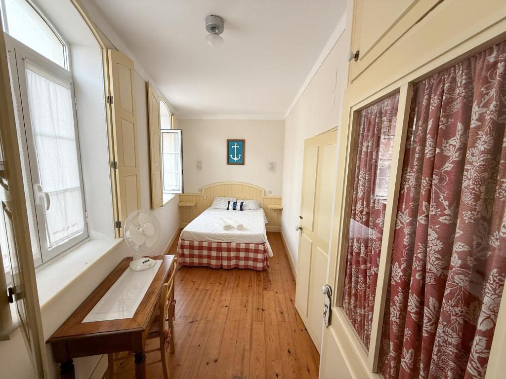 a bedroom with a bed and a table in a room at Casa das Ancoras Historic Beach Guesthouse in Buarcos Portugal in Bicas