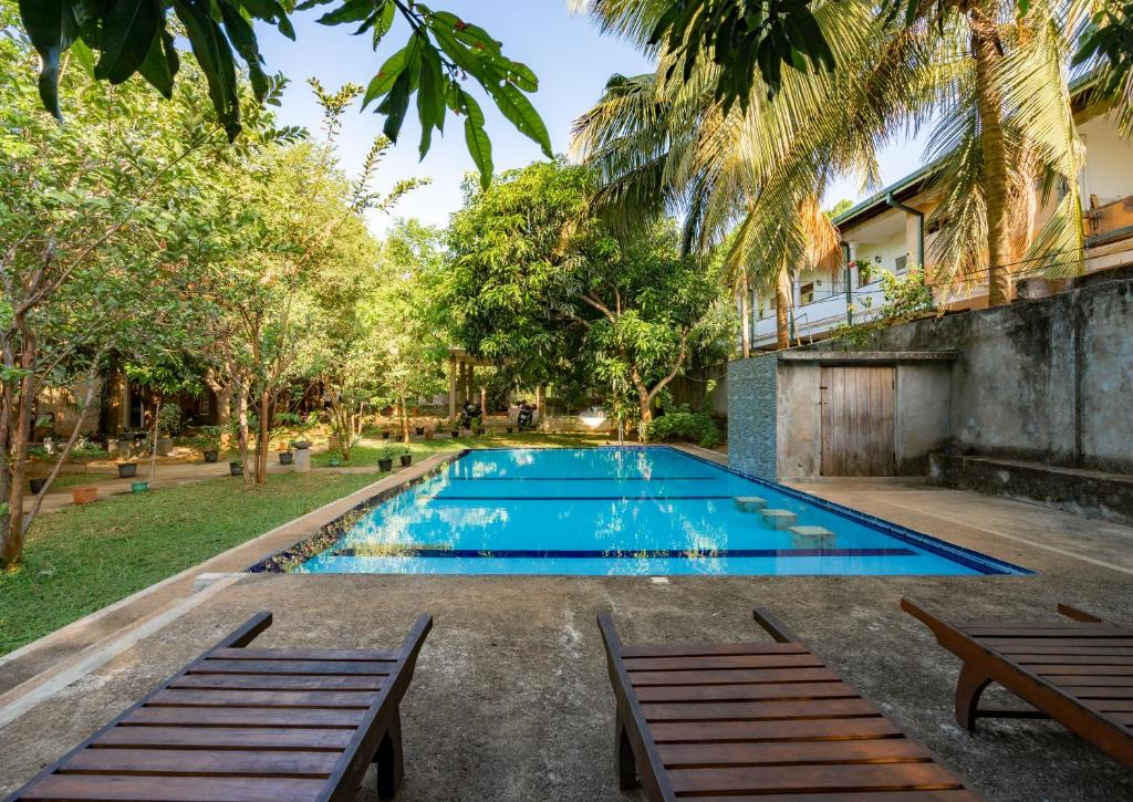 a swimming pool in the backyard of a house with two benches at Tropicara Resort in Sigiriya
