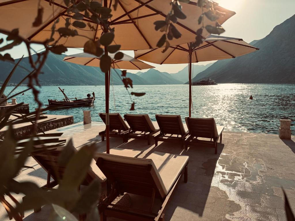 Un grupo de sillas y sombrillas en un muelle junto al agua. en Apartment Caserma, en Kotor