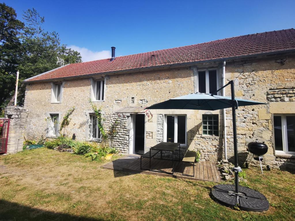 un ombrello davanti a una casa in pietra di Maison renovee en pierres séjour spacieux avec jardin et terrasse aménagée près Omaha beach & Bayeux à 5mn de la mer tous commerces a Commes