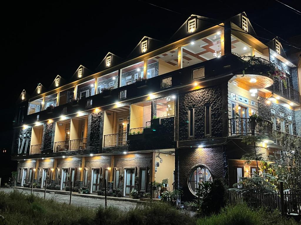 un grand bâtiment avec des lumières allumées la nuit dans l'établissement Sapo Rumbia Homestay, à Berastagi
