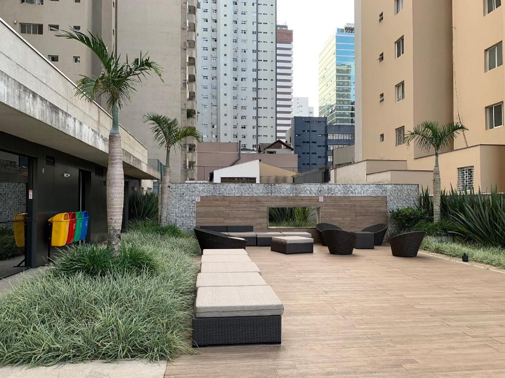 un cortile con divani e palme in una città di Apartamentos sofisticados no coração do Batel a Curitiba