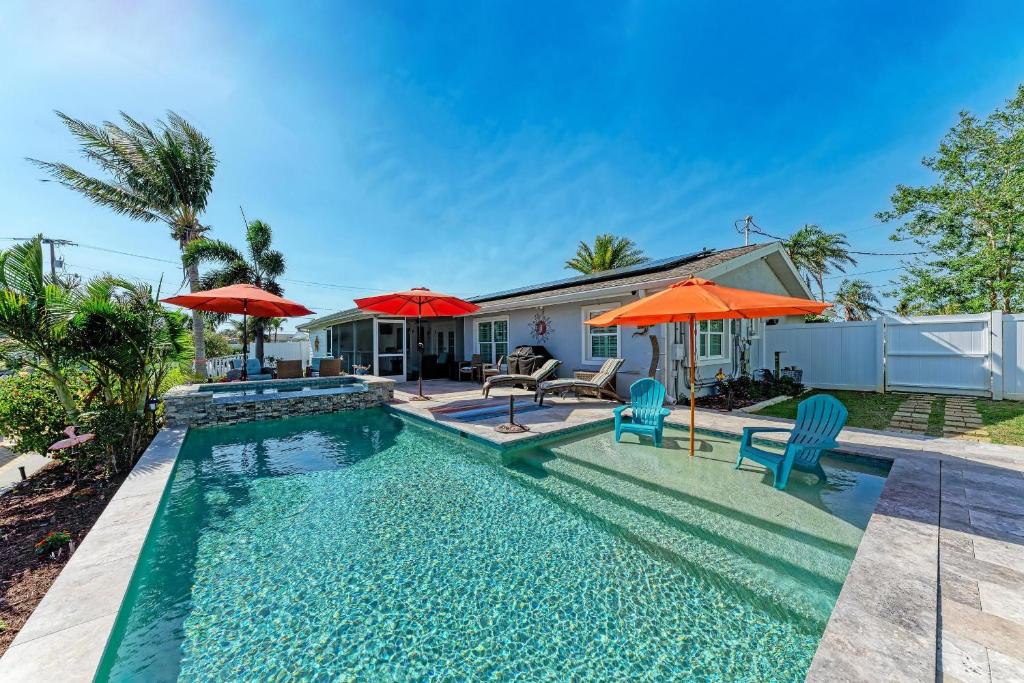 a swimming pool with two chairs and two umbrellas at Forget Me Knot in Bradenton