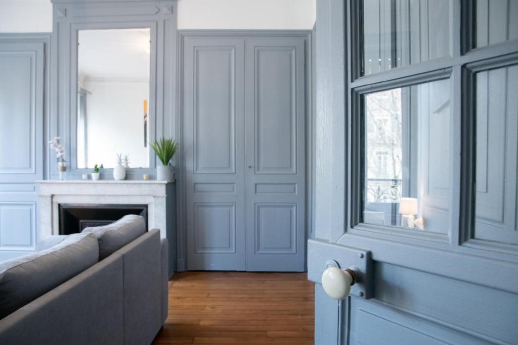 Una sala de estar con un sofá y una chimenea. en Appartement de charme dans le 6e - central, en Gare des Brotteaux