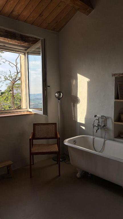 Un baño con bañera, silla y ventana. en Casa Cunicchio, en SantʼElpidio a Mare