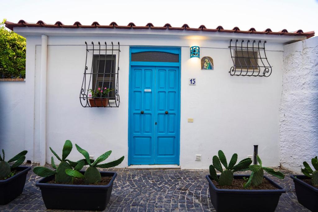 eine blaue Tür an einem weißen Gebäude mit Pflanzen in der Unterkunft Nido Mediterraneo in Procida