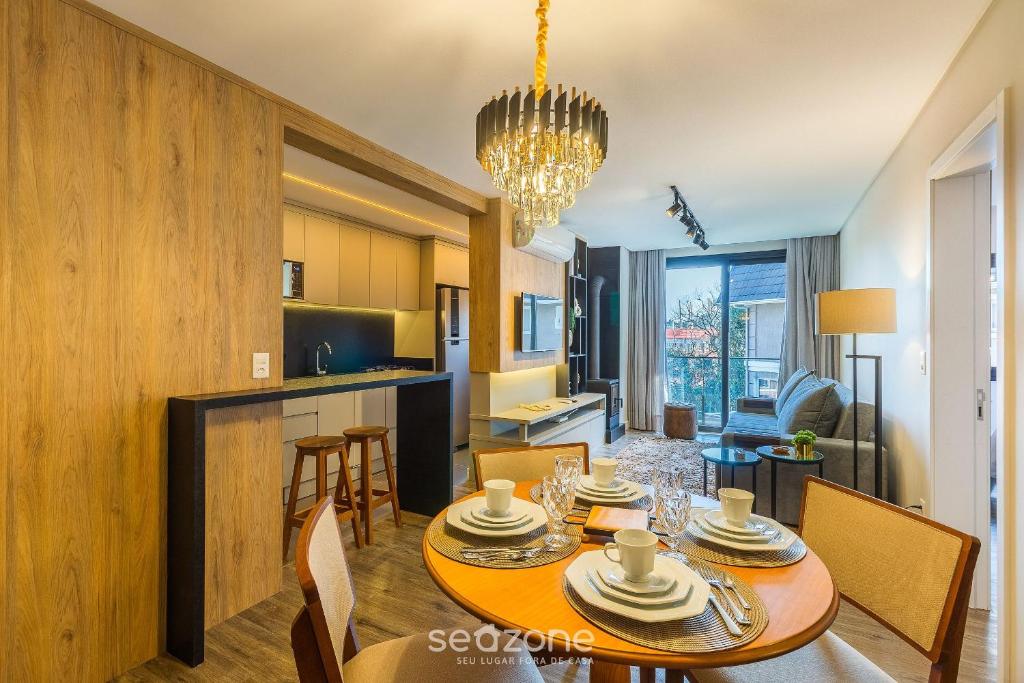 Apto Encantador c/ lareira em Gramado STA0305 في غرامادو: غرفة طعام ومطبخ مع طاولة وكراسي