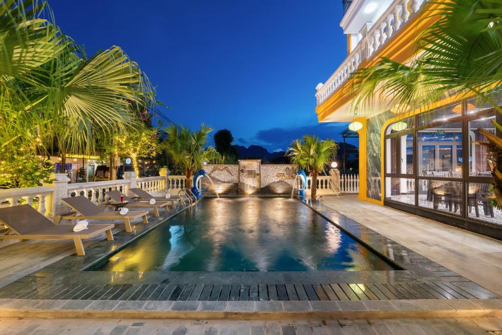 a resort pool with lounge chairs and a building at Tam Coc Babylon Hotel in Ninh Binh
