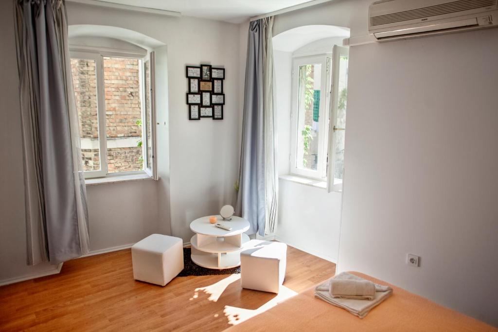 une chambre avec deux chaises blanches et deux fenêtres dans l'établissement West Wall Apartment, à Split