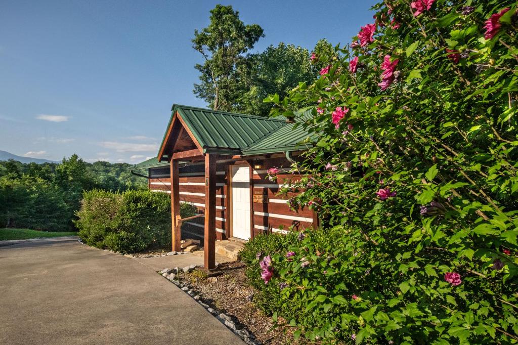 a small wooden building with a green roof and flowers at Views, King & Sofa Bed, Hot Tub, Firepit And Deck in Sevierville
