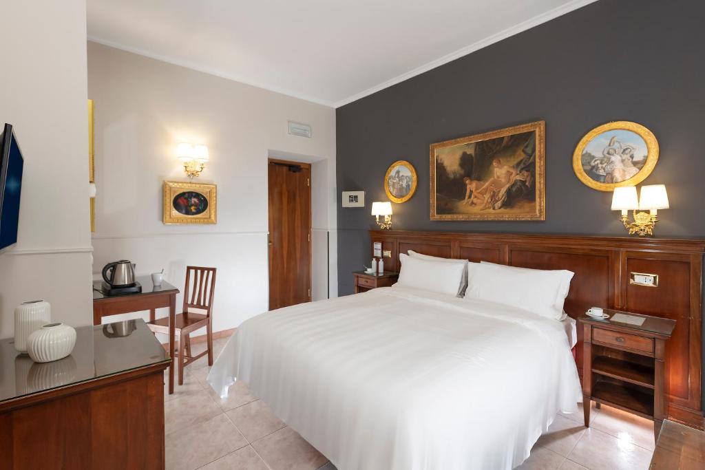 a bedroom with a large white bed and a desk at Hotel Des Artistes Roma in Rome