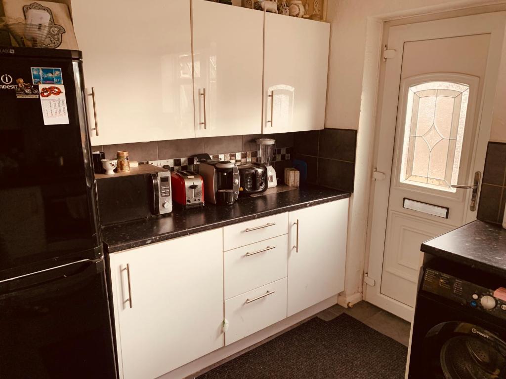 a kitchen with white cabinets and a black refrigerator at The Glenton Getaway in Peterborough