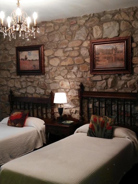 a bedroom with two beds and a stone wall at Posada Valle De Guriezo in Ríoseco