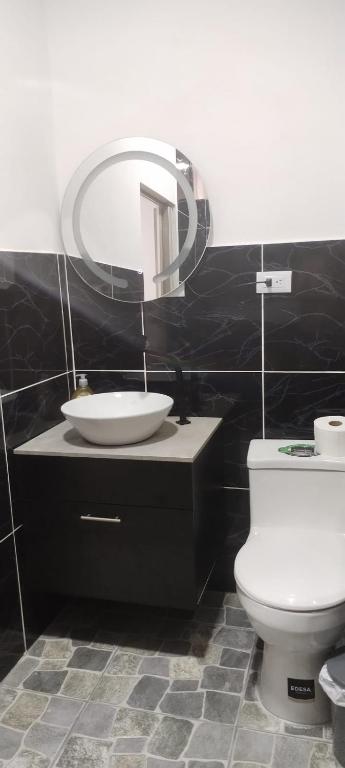a bathroom with a sink and a toilet and a mirror at Departamento Samir in Manta