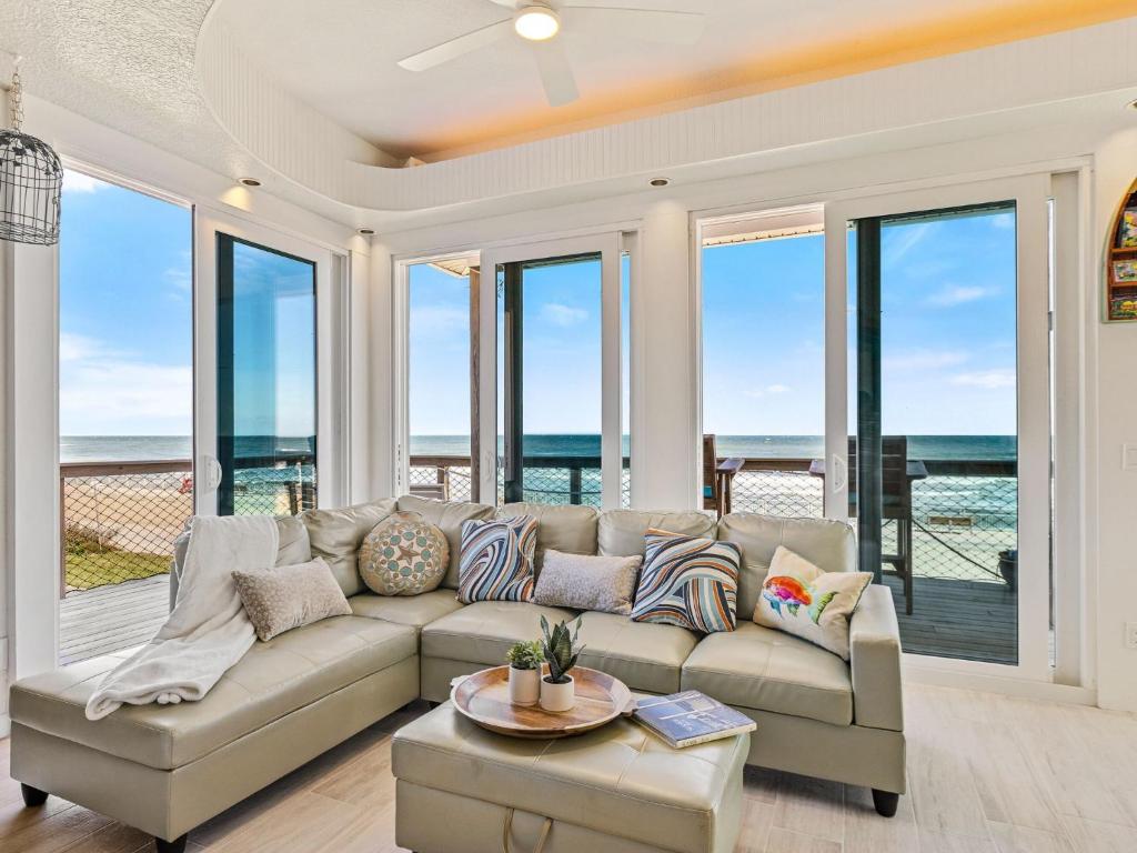 a living room with a couch and large windows at 'Little Latitude' High Tide - Oceanfront Home with Crow's Nest! in New Smyrna Beach