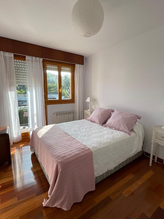 a bedroom with a large bed with pink pillows at El jardín de Max, apartamento céntrico con jardín privado y parking in Comillas