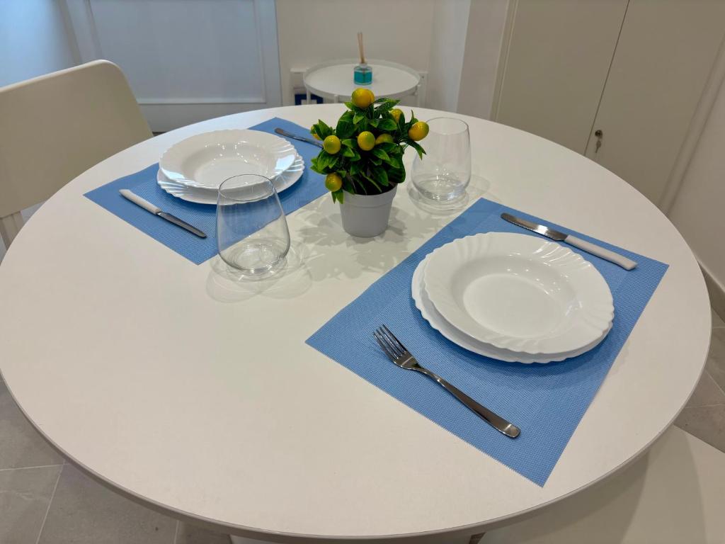 a white table with white plates and a blue napkin at Kupe Luxury Loft in SantʼAgata sui Due Golfi