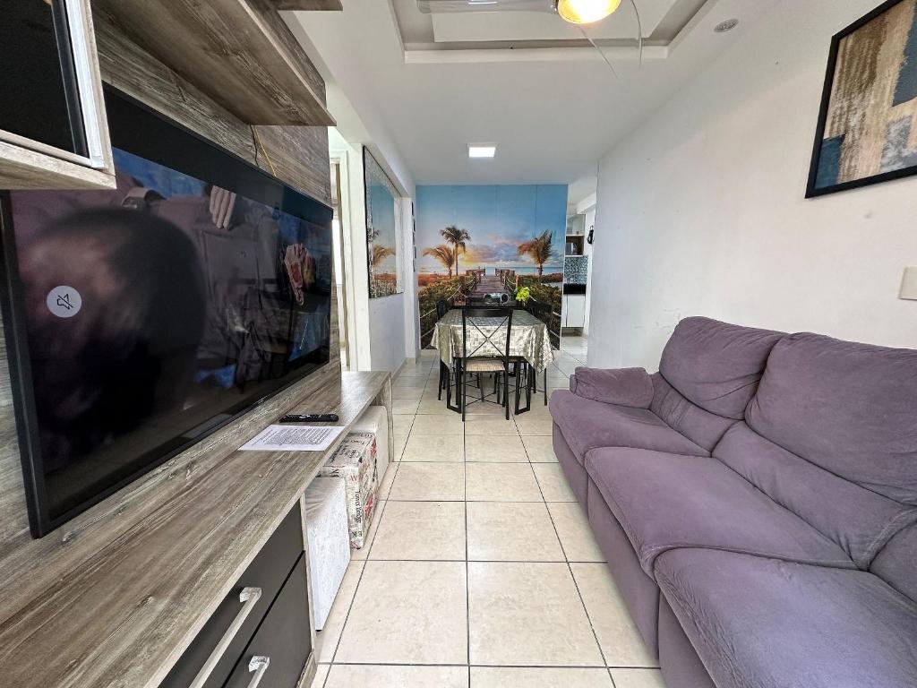 a living room with a purple couch and a tv at Ocian: 2 quartos, suíte, piscina e perto da praia in Samaritá