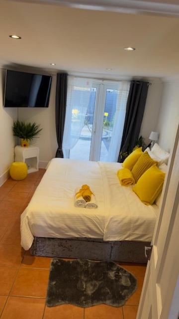 Un dormitorio con una cama con almohadas amarillas y una ventana. en Peaceful Springfield Studio, en Chelmsford