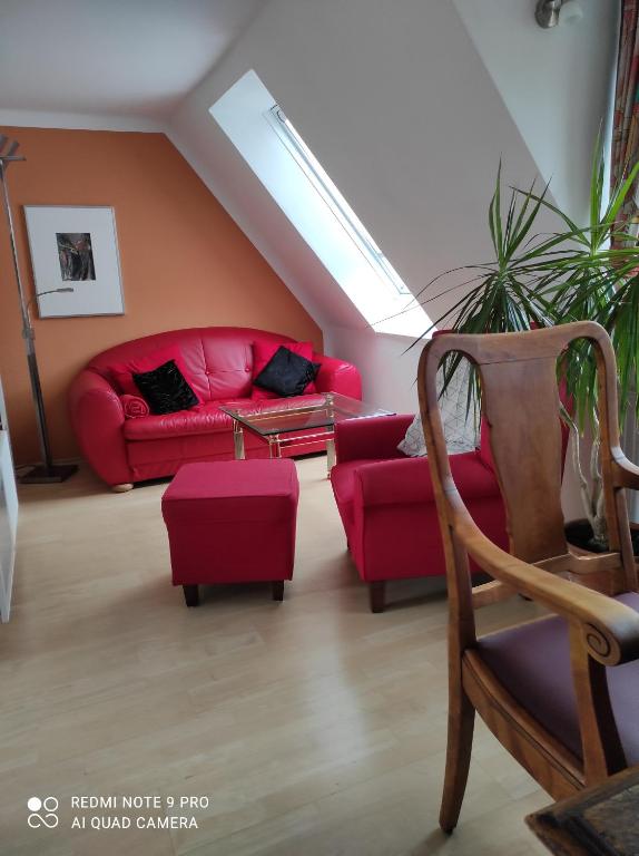 ein Wohnzimmer mit einem roten Sofa und einem Sessel in der Unterkunft Haus Sonnenschein in Heikendorf