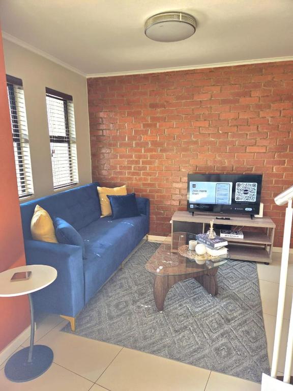 a living room with a blue couch and a brick wall at 1 bed Apartment in hatfield in Pretoria
