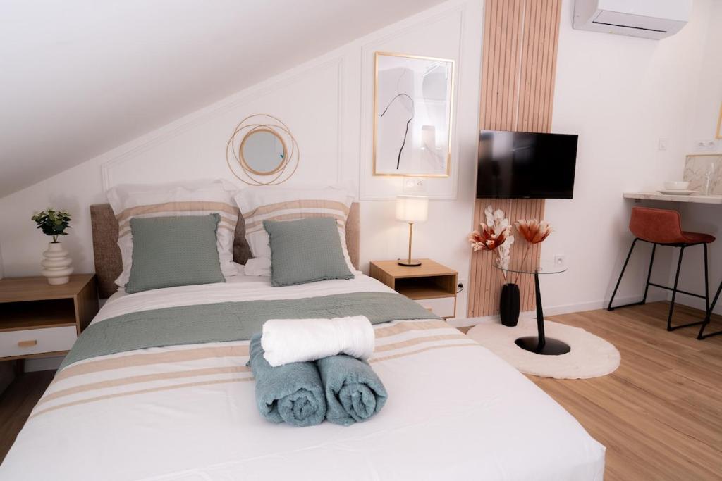 a bedroom with a white bed with towels on it at Ô Perchoir des rêves au centre Millau in Millau