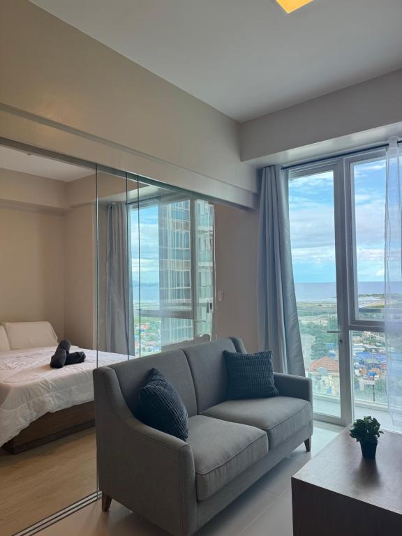 Punta Engañoにある3 Js Condo Rental 8NB Mactan Newtownのソファとベッドと窓のあるリビングルーム