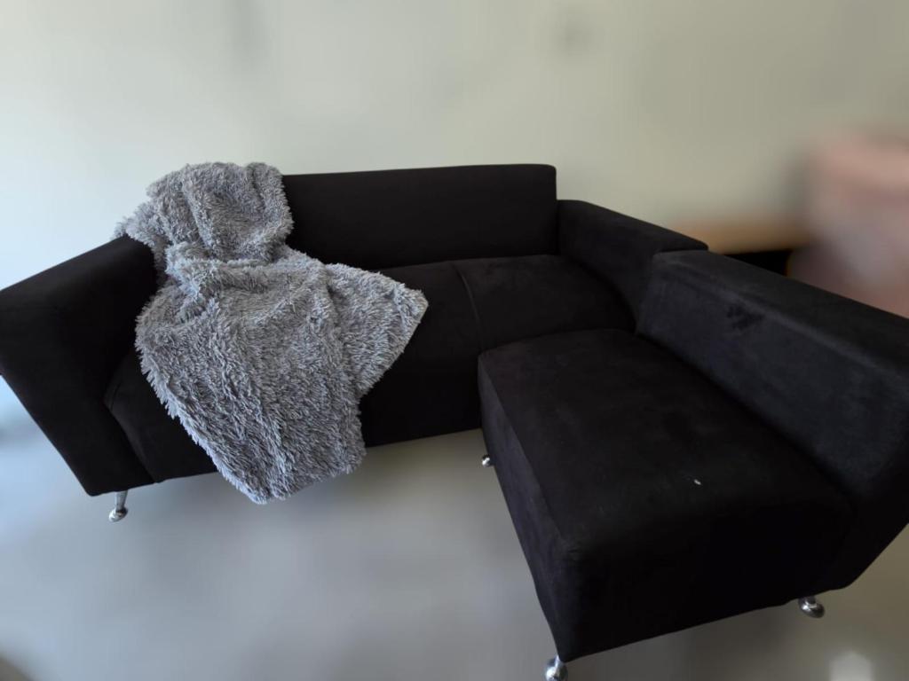 Un sofá negro con una bufanda gris encima. en Juanita, en Buenos Aires